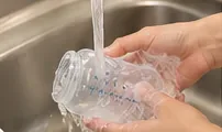 清洗後，用乾淨的流水沖洗透明的嬰兒奶瓶。