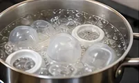拆解後的嬰兒奶瓶零件浸泡在不銹鋼鍋內的沸水中。