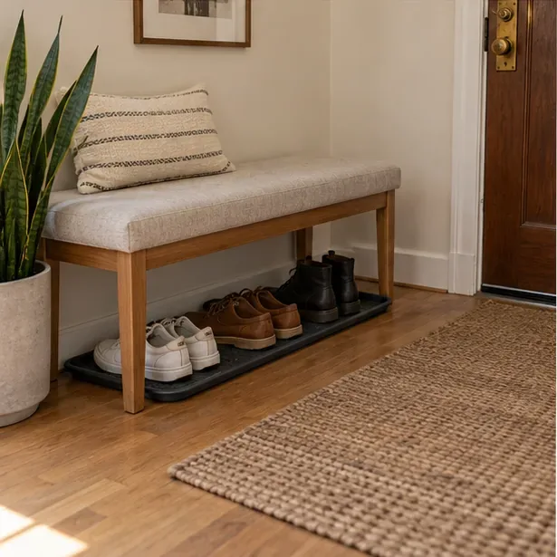 A slim bench stands above a tray holding a few pairs of shoes, leaving the entrance walkway open.