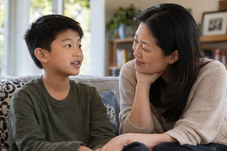 A child speaks openly with a parent on the couch, and the parent listens with a warm expression.