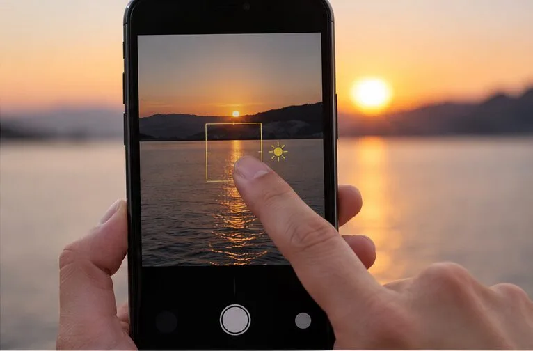 A finger presses and holds on a phone camera preview before recording to set focus and exposure